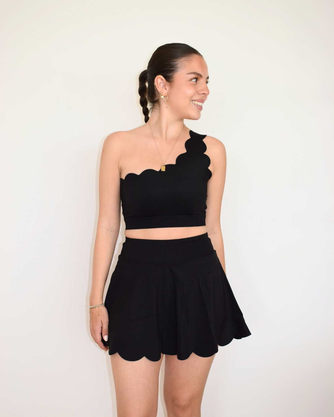 Modelo usando The Edge One-Shoulder Bra negro de Muv&Glow, top deportivo asimétrico con soporte medio.