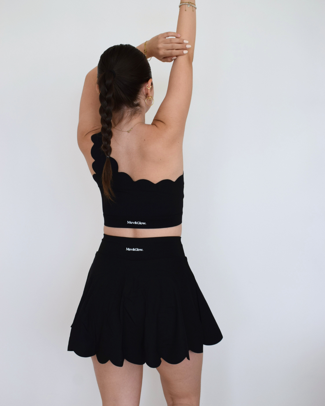 Vista trasera de The Edge Skirt negro de Muv&Glow, short interior cubierto con falda plisada de caída suave.