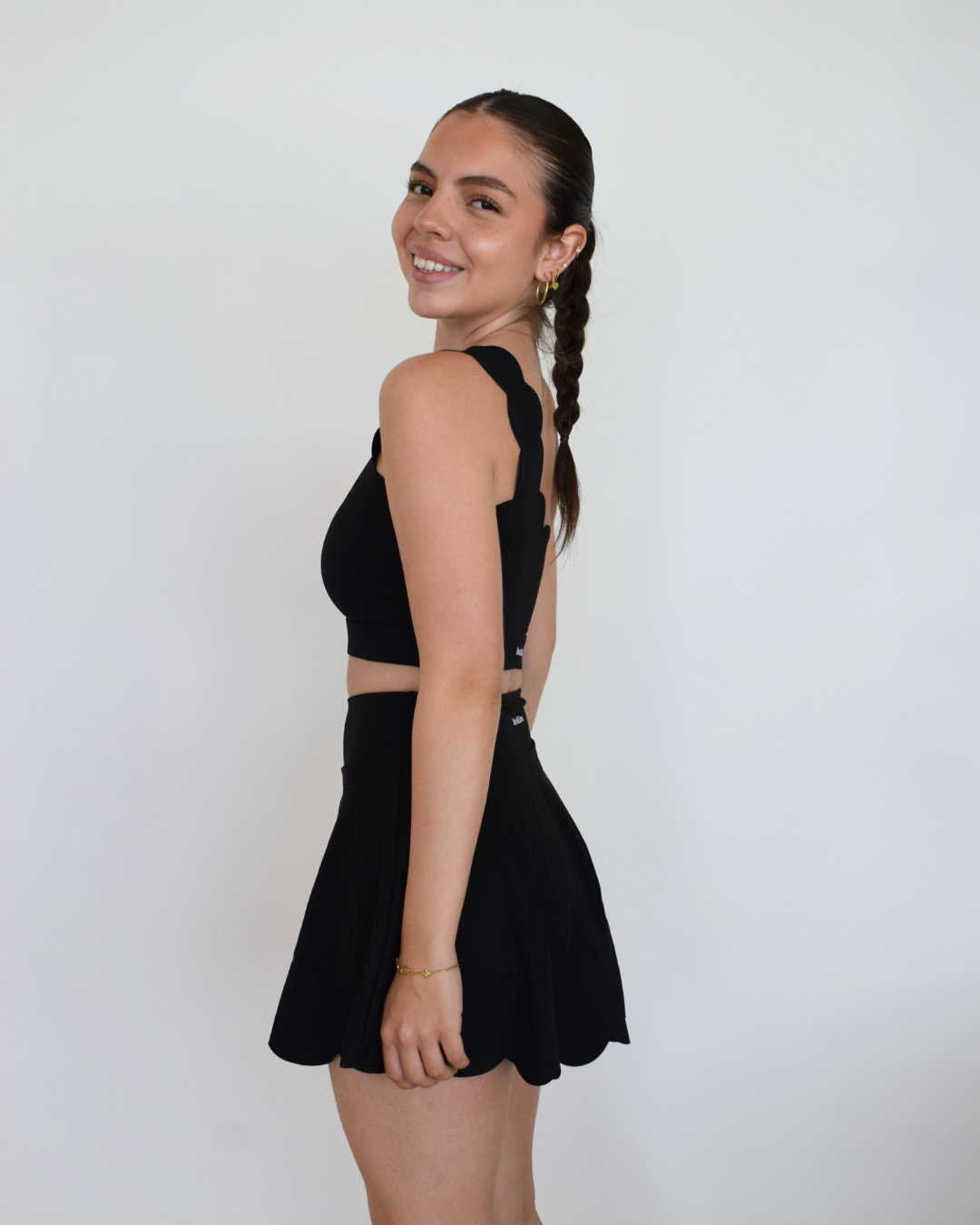 Perfil de modelo luciendo The Edge Skirt negro de Muv&Glow, falda cómoda y estilizada para entrenar o pasear.