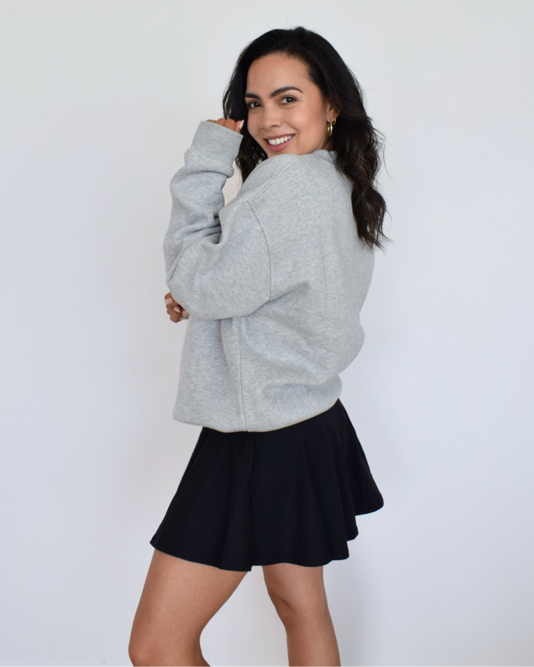 Modelo usando el Essential Pullover gris de Muv&Glow, sudadera amplia y relajada para combinar con activewear.
