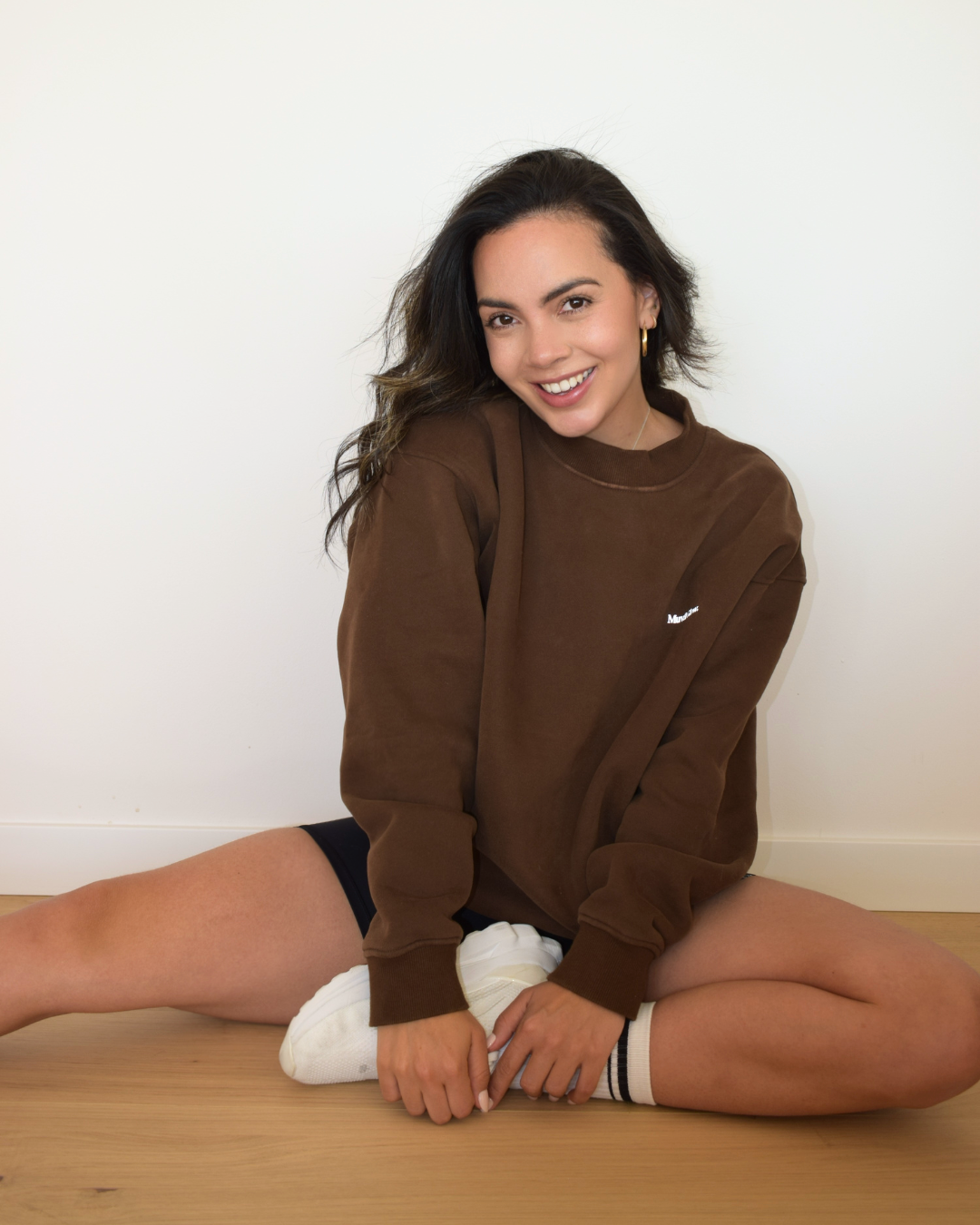 Modelo sentada usando el Essential Pullover color espresso de Muv&Glow