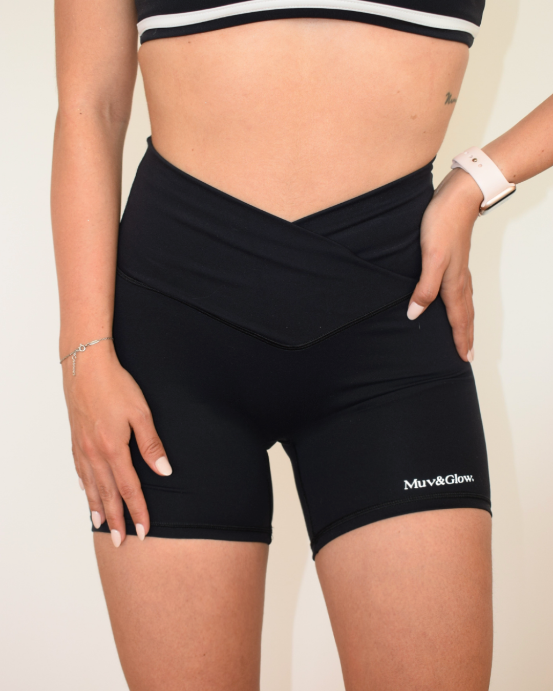 Mujer usando los core Shorts negros de Muv&Glow, vista frontal con cintura cruzada.