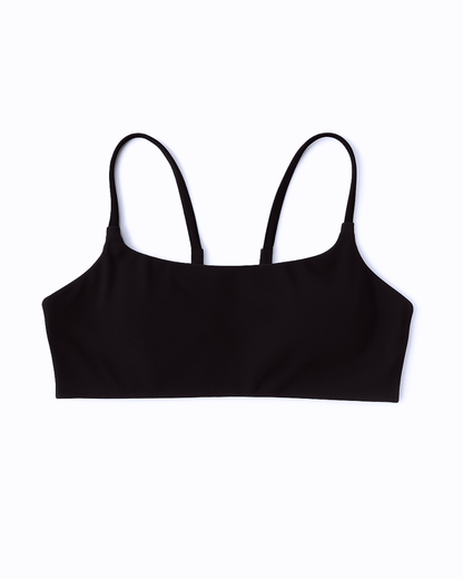 Flat lay del Core Bra negro de Muv&Glow sobre fondo blanco, top deportivo ideal para yoga o pilates.
