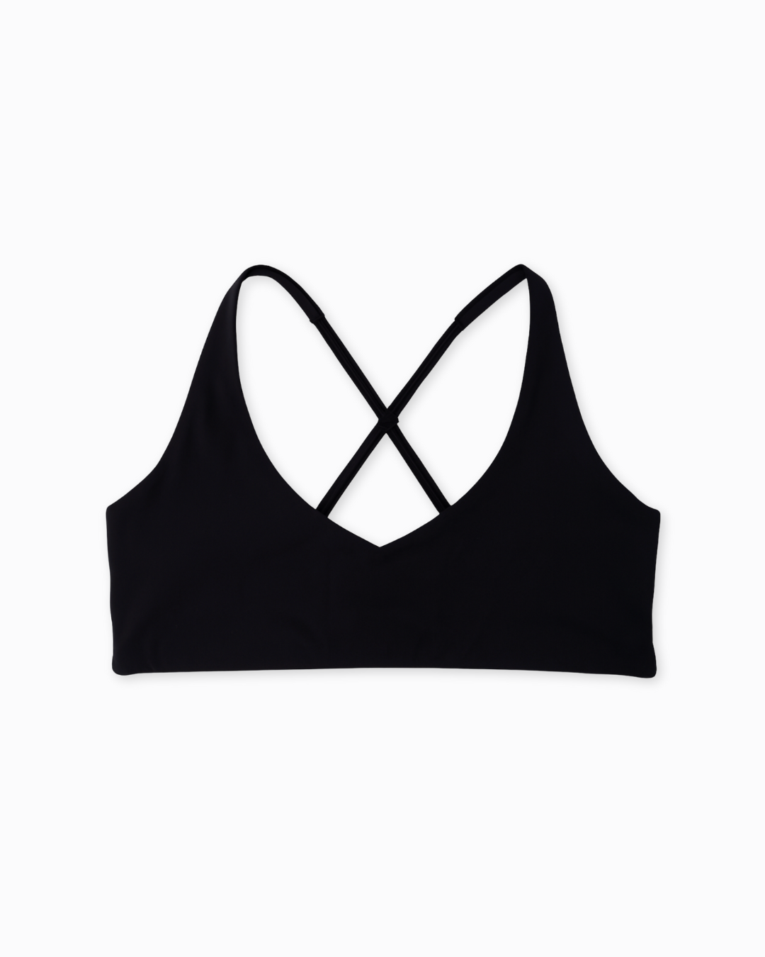 Flat lay del Core Loop Bra negro de Muv&Glow sobre fondo blanco, diseño con tirantes cruzados y sin costuras.
