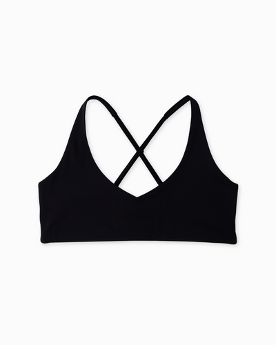Flat lay del Core Loop Bra negro de Muv&Glow sobre fondo blanco, diseño con tirantes cruzados y sin costuras.

