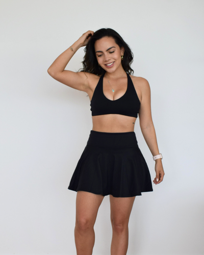 Vista frontal del Core Loop Bra negro de Muv&Glow, top deportivo con tirantes cruzados y escote en V.
