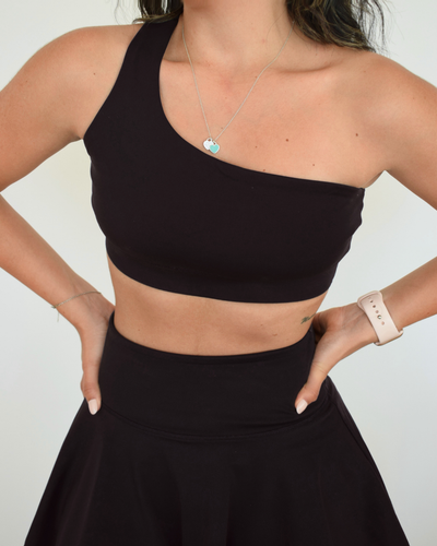 Detalle frontal del Core One-Shoulder Bra negro de Muv&Glow, acabado limpio con escote recto y pretina firme.
