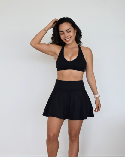 Modelo usando The Core Skirt negro de Muv&Glow, falda deportiva con short interior y cintura alta
