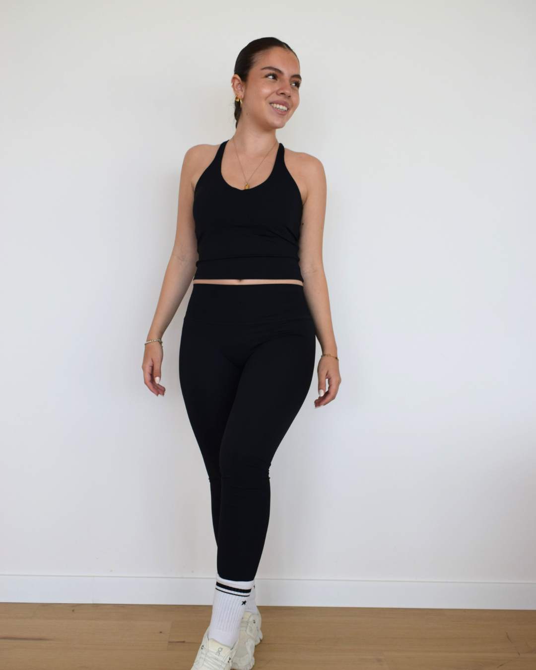 Modelo usando The Core Twist Top negro de Muv&Glow, top largo con escote redondo y soporte medio.