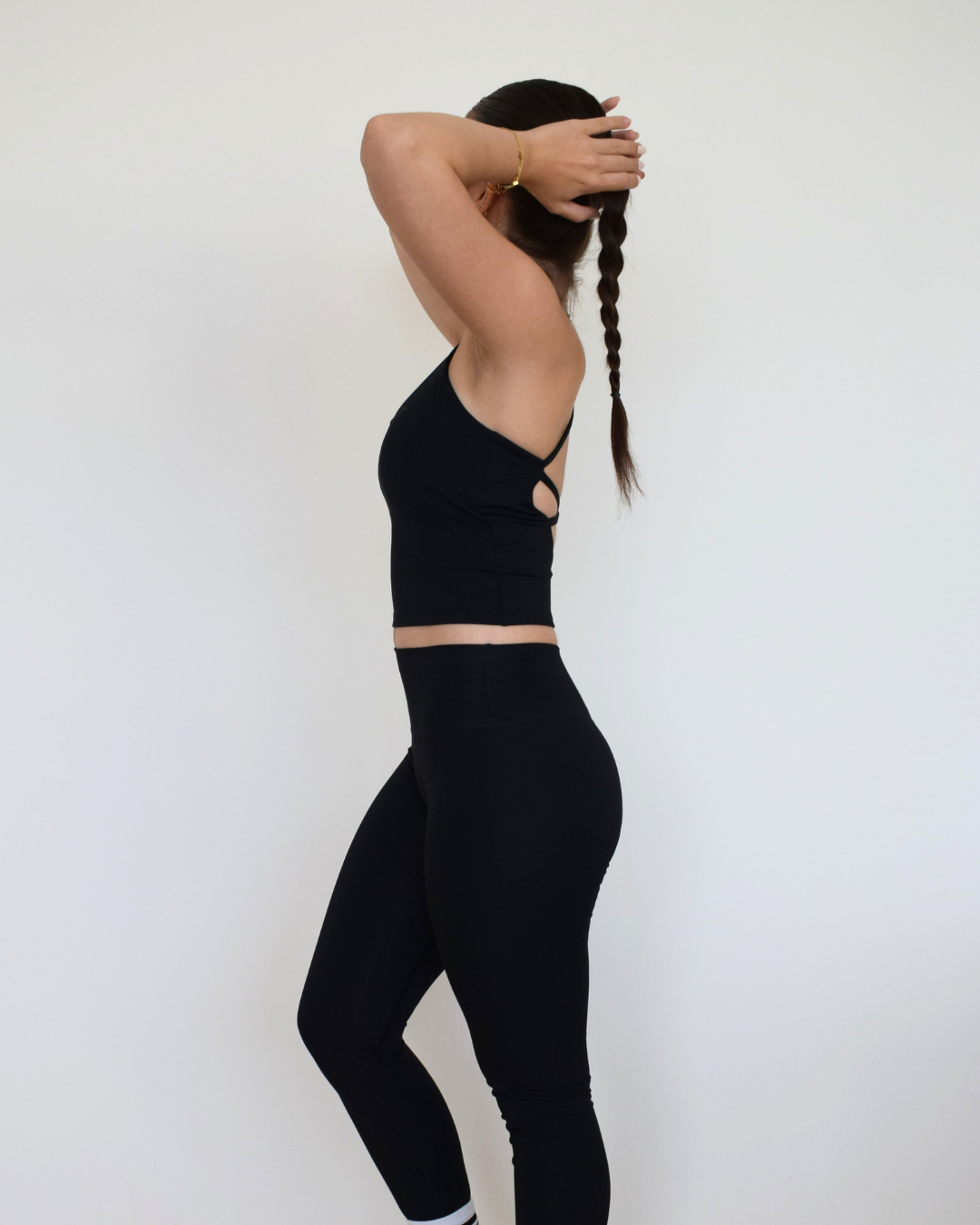 Vista lateral del Core Twist Top negro de Muv&Glow, top deportivo ajustado y cómodo para entrenar.