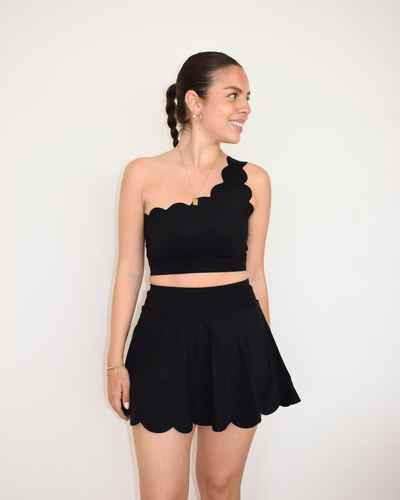 Modelo usando The Edge One-Shoulder Bra negro de Muv&Glow, top deportivo asimétrico con soporte medio.

