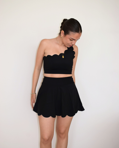 Vista lateral de The Edge Skirt negro de Muv&Glow, diseño femenino con pretina alta y vuelo ligero.

