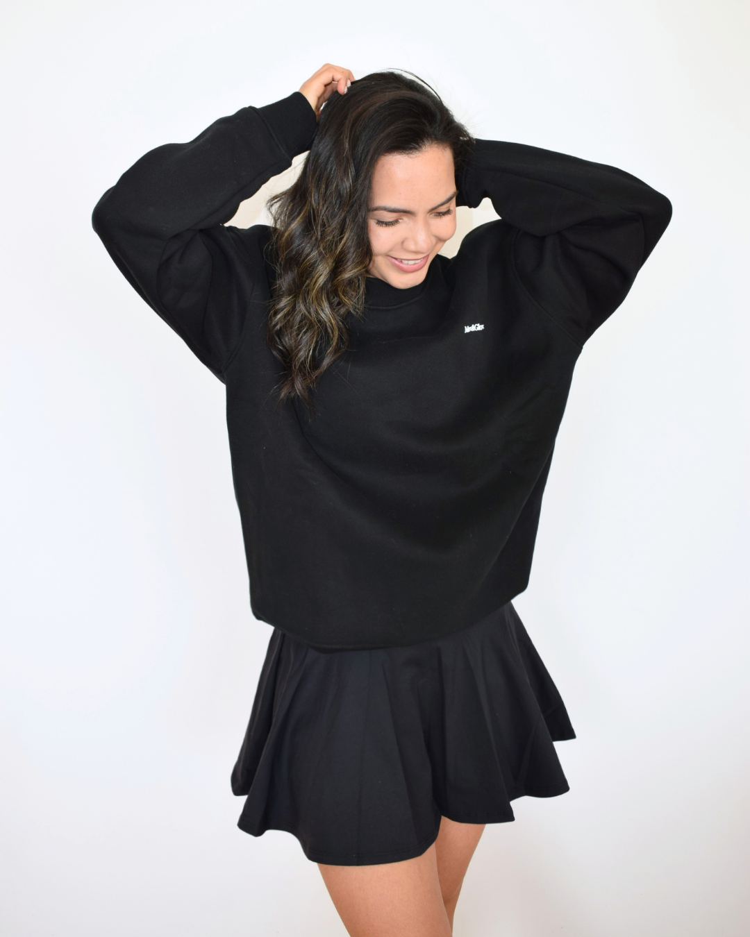 Vista frontal del Essential Pullover negro de Muv&Glow, diseño relajado con cuello redondo y mangas largas.
