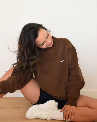 Modelo con el Essential Pullover de Muv&Glow en espresso, apoyada sobre el suelo
