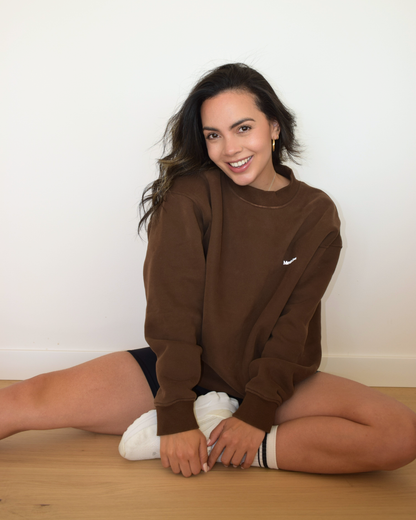 Modelo sentada usando el Essential Pullover color espresso de Muv&Glow
