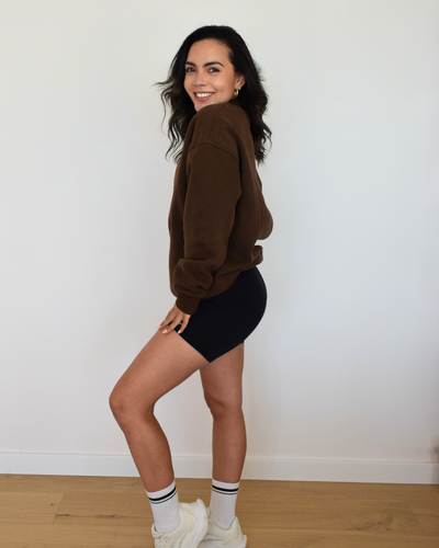 Modelo de pie con el Essential Pullover espresso, estilo relajado
