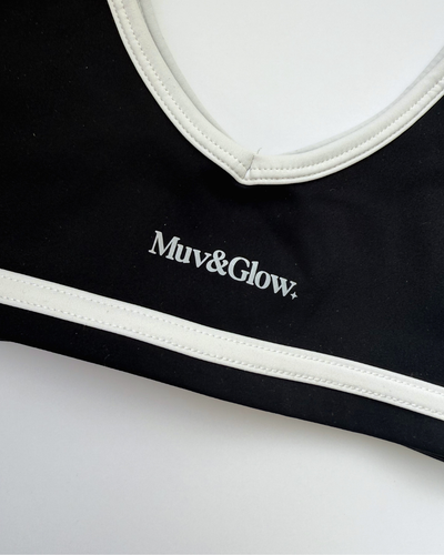 Detalle del borde blanco y logo en el Icon Bra negro de Muv&Glow
