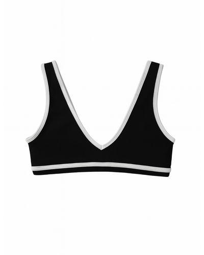 Flat lay del Icon Bra negro con ribete blanco de Muv&Glow
