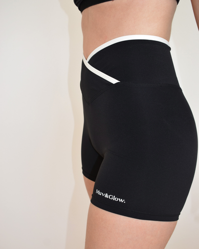Vista lateral de los Icon Shorts negros con ribete blanco y logo Muv&Glow
