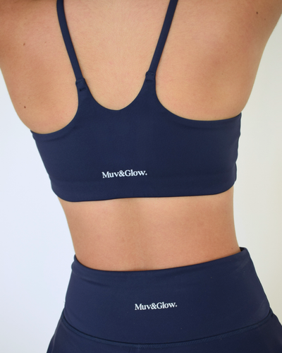Detalle de la espalda con logo Muv&Glow usando falda y top navy.