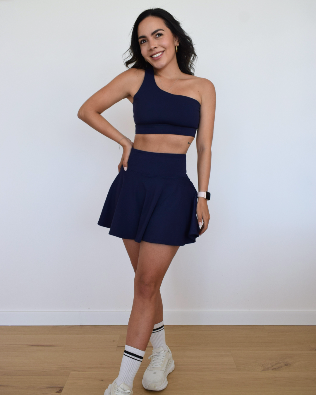 Mujer usando la falda The Core Skirt navy de Muv&Glow, vista frontal.