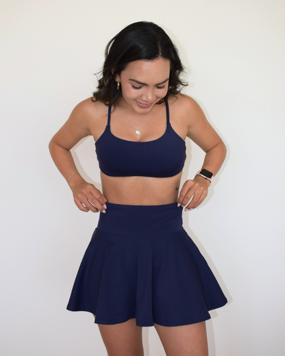 Mujer posando de frente con la falda The Core Skirt navy de Muv&Glow y top a juego.