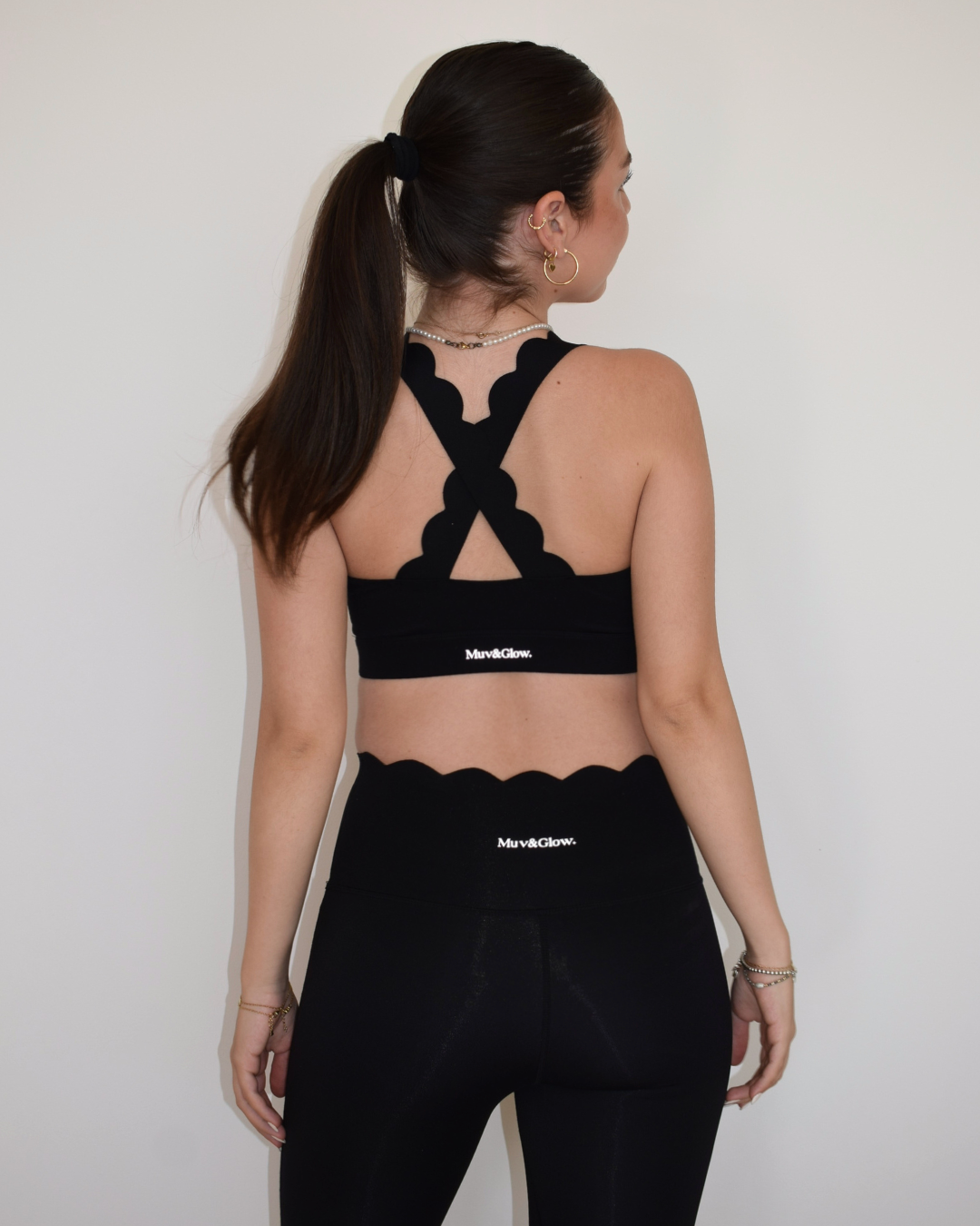 Mujer mostrando la parte trasera del conjunto negro Muv&Glow con The Edge Bra.
