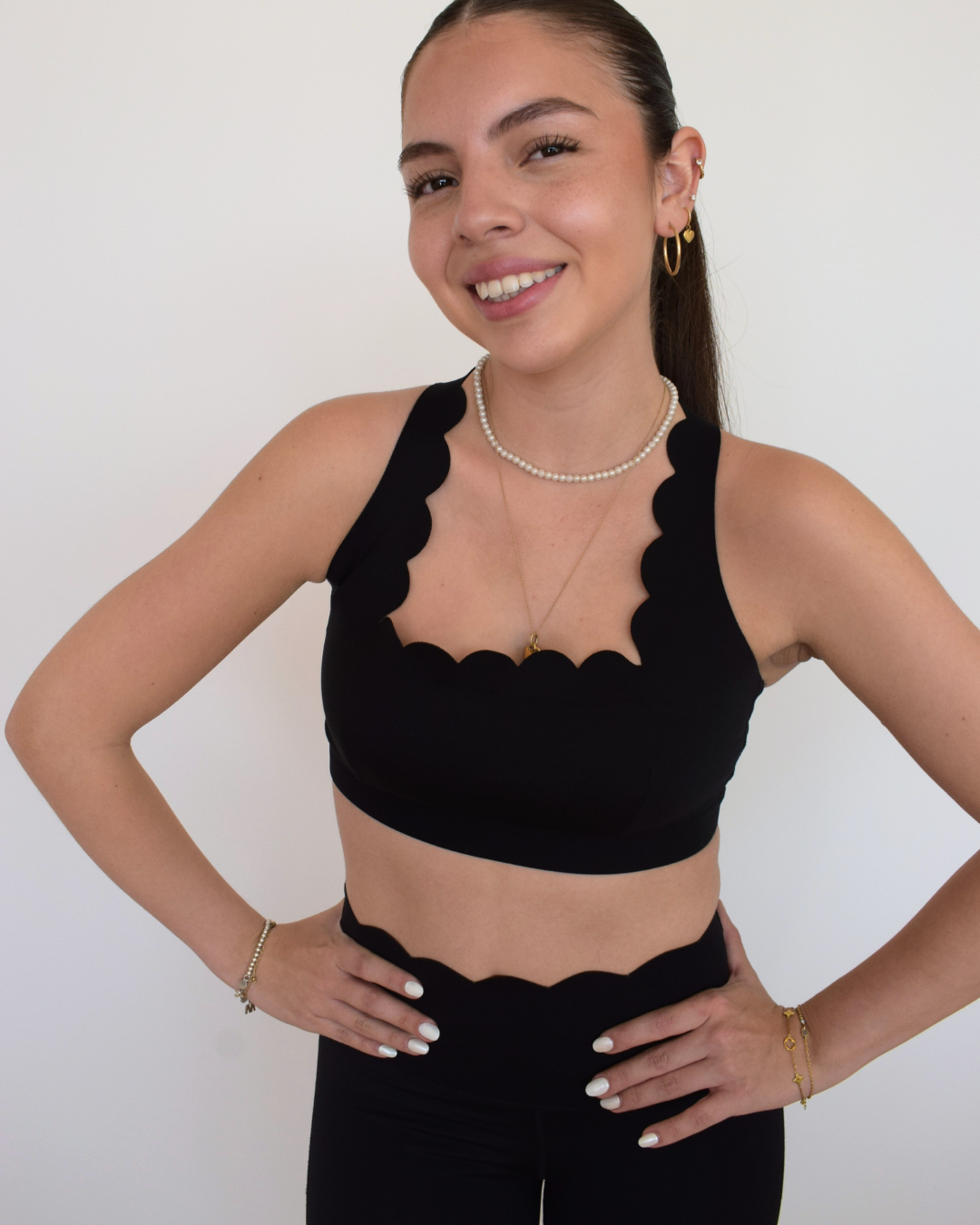 Vista en ángulo tres cuartos del The Edge Bra negro de Muv&Glow en conjunto con leggings.
