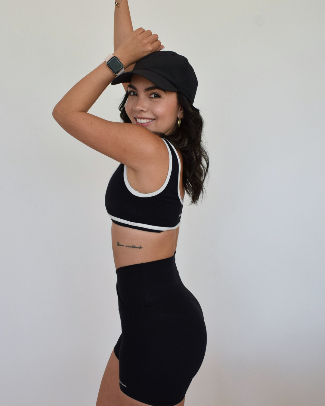 Mujer con conjunto negro Muv&Glow, vista trasera, usando bra Icon y shorts a juego.