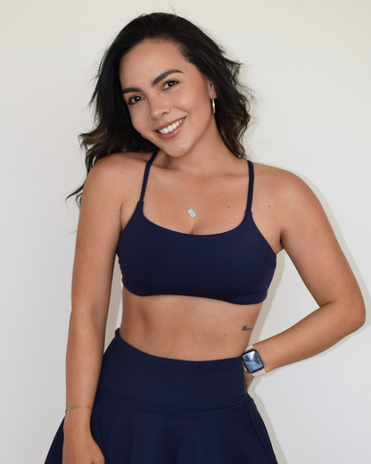 Modelo de pie luciendo el Core Bra y la falda deportiva navy